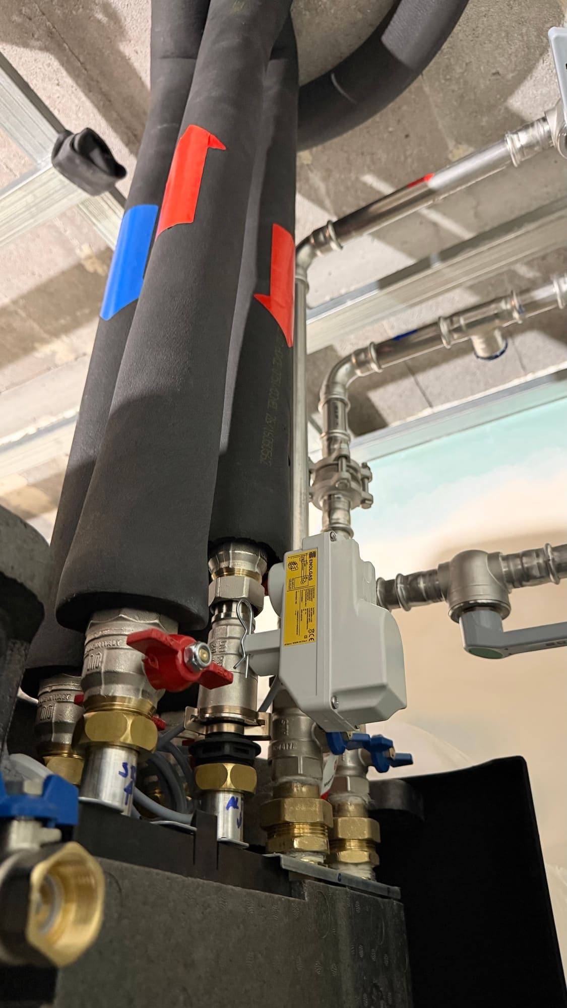 Hydraulic connections above the hydrokit: insulated pipes marked flow and return, valves and filter
