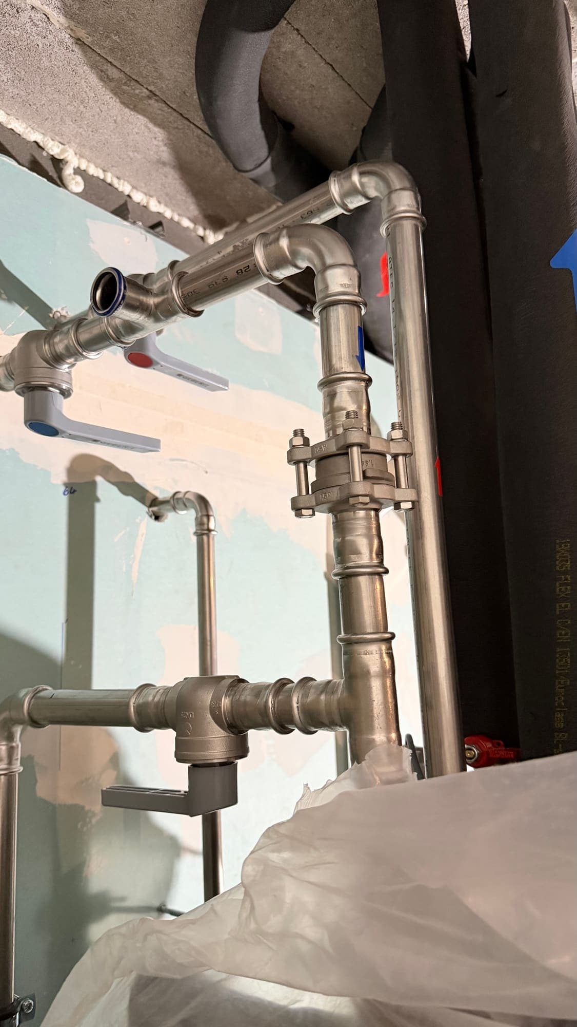Stainless steel pipes with press-fit joints, elbows and a flange in the plant room