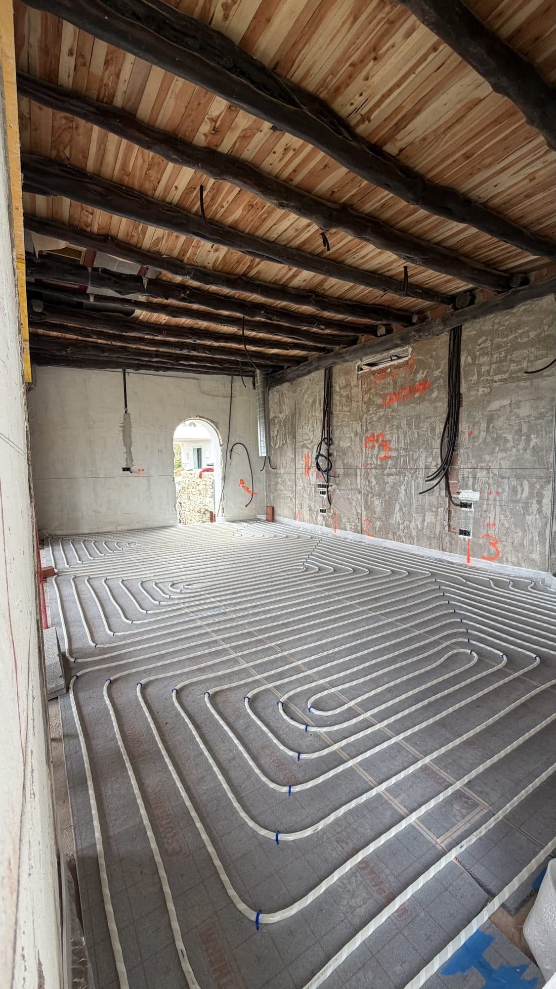 Underfloor heating pipe laid in a spiral on self-fixing insulation board, before the screed