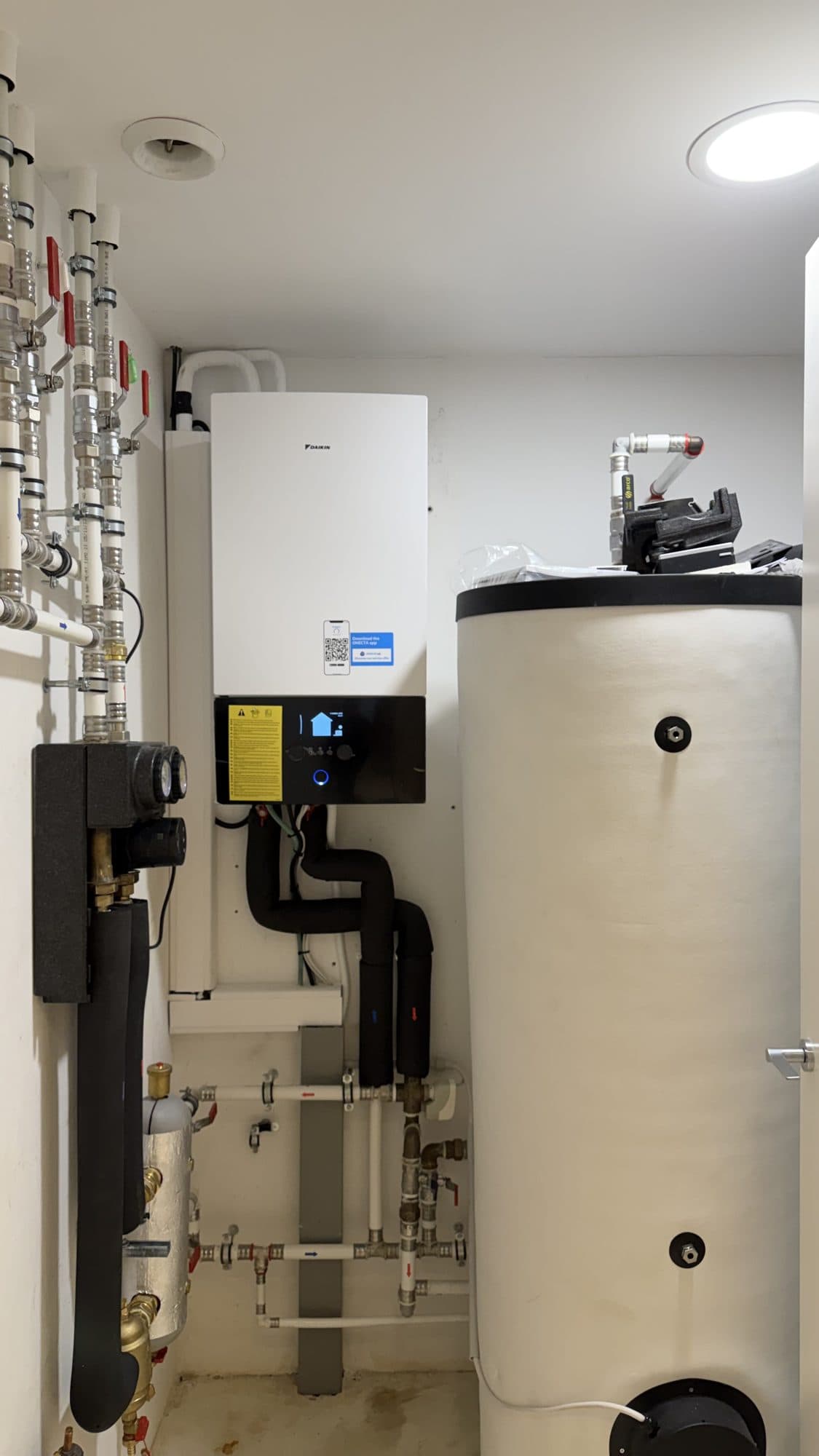 Sala técnica con la unidad interior de la bomba de calor, el depósito de agua caliente y los colectores